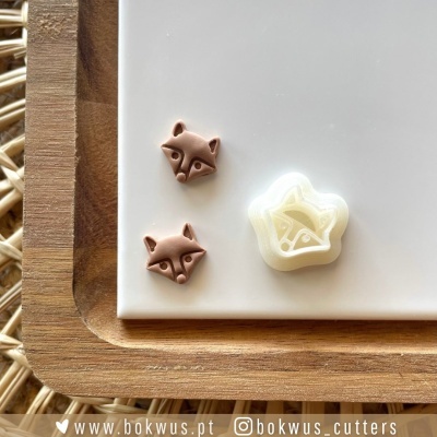 Três cortadores de biscoito com desenhos de raposa e estrela sobre bandeja branca e base de madeira