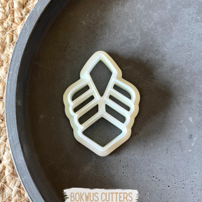 Cortador de bolachas branco em forma de folha num prato cinzento.