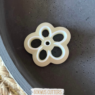 Cortador branco em forma de flor sobre superfície escura com texto BOKWUS CUTTERS