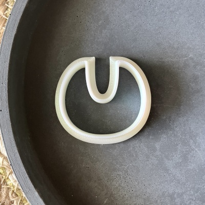 Forma metálica branca circular com abertura sobre superfície cinza