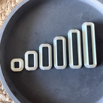 Conjunto de seis moldes retangulares brancos e cinzentos sobre prato preto redondo.