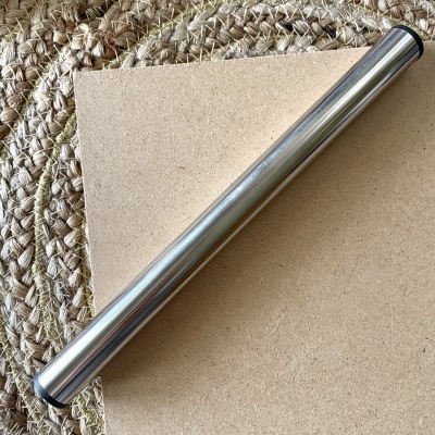 tubo cilíndrico metálico prateado sobre madeira e tapete tecido