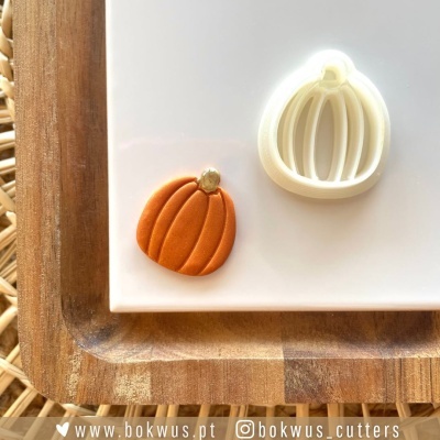 Cortador e biscoito em forma de abóbora sobre tabuleiro de madeira