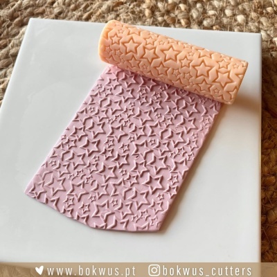 Rolo para pasta com padrão de estrelas cor de pêssego sobre pasta rosa e superfície branca