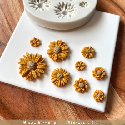 Molde de silicone com flores esculpidas amarelas e castanhas sobre placa branca