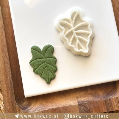 Cortador de massa em forma de folha e massa texturizada no tabuleiro de madeira