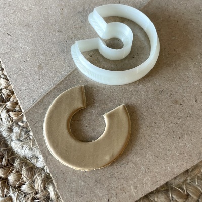 Peças circulares abertas em plástico branco e material bege sobre madeira clara com tapete de fibra natural