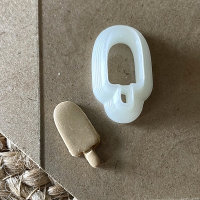 Molde branco de plástico para gelado com gelado castanho em pauzinho