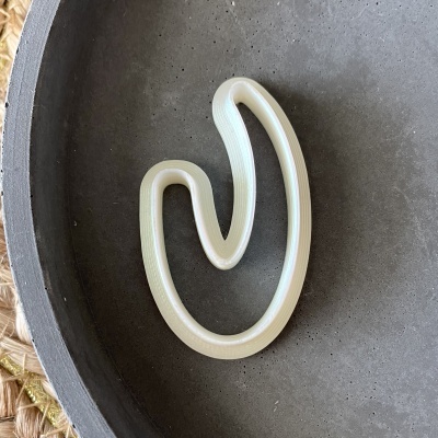 Gancho plástico creme dentro de recipiente cinzento sobre superfície têxtil trançada