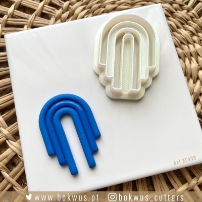 Dois cortadores de plástico em forma de arco azul e branco num prato branco sobre uma superfície de vime.
