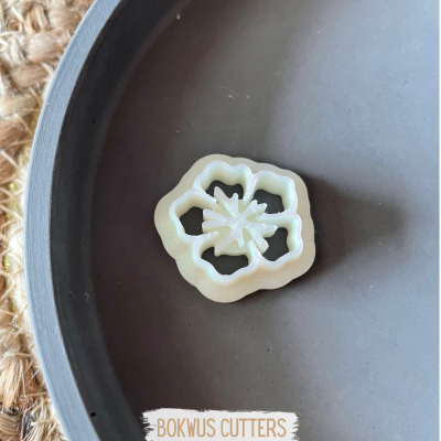 Cortador de bolachas em forma de flor branco sobre superfície preta