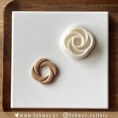 Duas flores decorativas branca e castanha sobre base branca e bandeja de madeira