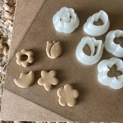 Conjunto de cortadores de massa de plástico branco com biscoitos em várias formas em cima de base de cartão castanho