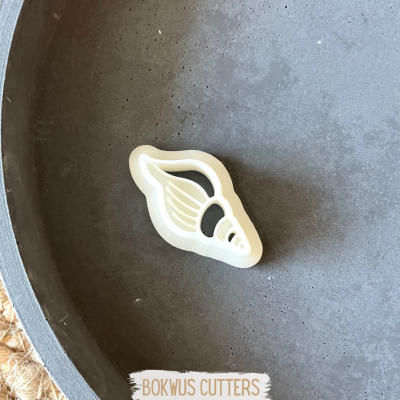 Cortador de bolos branco em forma de concha num prato cinzento