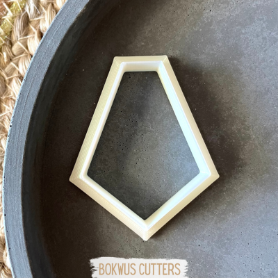 Cortador de biscoitos pentagonal branco sobre superfície cinza e tapete de tecido trançado