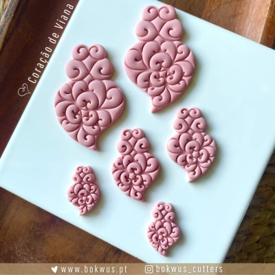 Cortantes decorativos rosa com padrão arabesco em tabuleiro branco