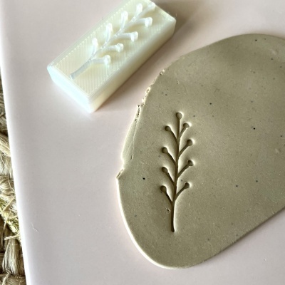 Carimbo branco em plástico com padrão de ramo, argila cinzenta em superfície rosa