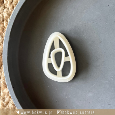 Cortador de plástico branco em forma oval com divisões internas sobre superfície cinzenta.