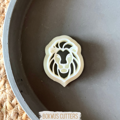 Cortador de bolacha em forma de cabeça de leão branco numa tigela cinza.
