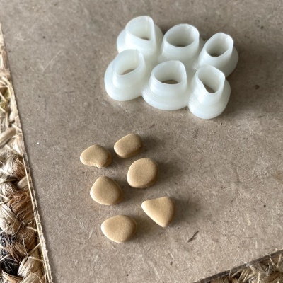 Pequenos objetos brancos de plástico e comprimidos beige sobre superfície castanha