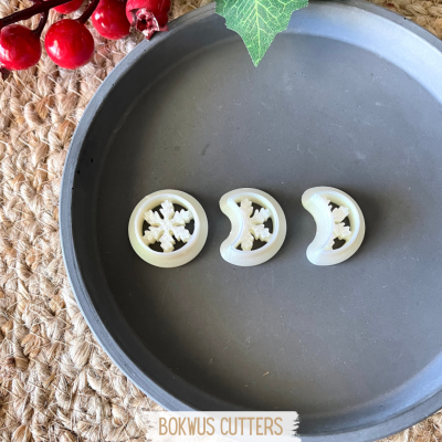 Três cortadores de massa em forma de floco de neve numa travessa cinza