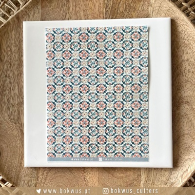 Azulejo quadrado com padrão geométrico azul e rosa sobre prato de madeira