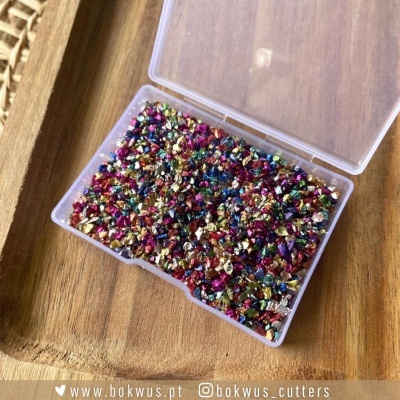 Granulado metálico colorido num estojo transparente sobre madeira
