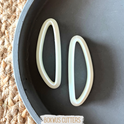 Dois cortadores de plástico branco em forma de meia-lua sobre superfície preta e etiqueta 'BOKWUS CUTTERS'