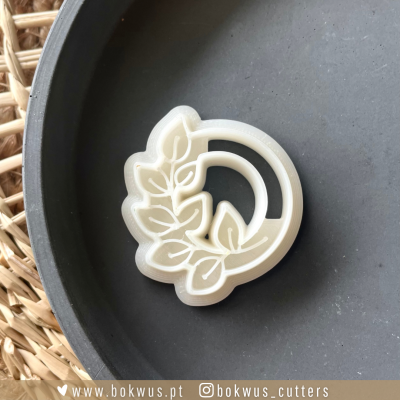 Cortador de biscoitos branco com design de folhas sobre base preta