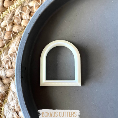 Cortador de massa branco em forma de arco sobre prato cinza e esteira de fibra natural com texto BOKWUS CUTTERS