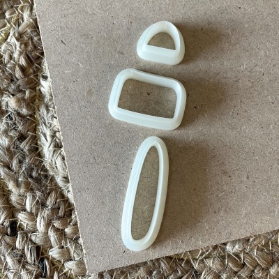 Três fivelas de plástico branco em diferentes formas sobre superfície castanha