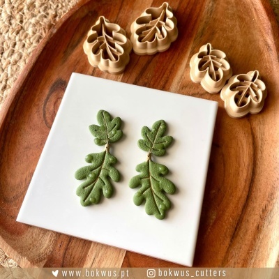 Moldes cortantes em forma de folhas e peças moldadas verdes sobre azulejo e tábua de madeira