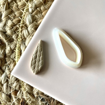 Dois pingentes em forma de gota sobre prato rosa claro e tapete de fibras trançadas