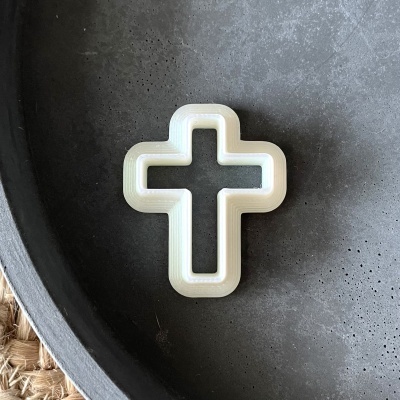 Cruz branca decorativa numa superfície metálica escura