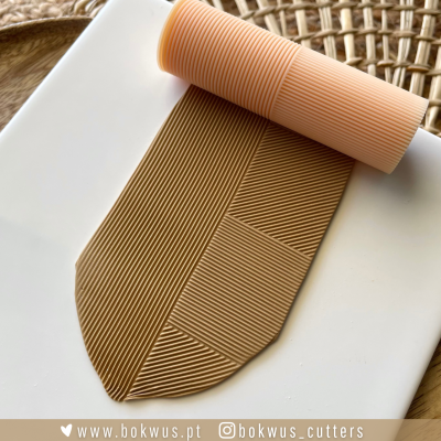 Ferramenta de corte para pastelaria em material bege claro com padrão de linhas paralelas, sobre superfície branca