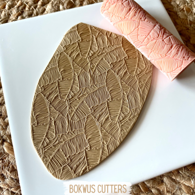 Rolo texturizador cor-de-rosa com padrão de folhas e massa marrom clara estampada