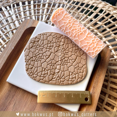 Barra e tapete de massa polimérica com textura rachada em prato branco e suporte de madeira