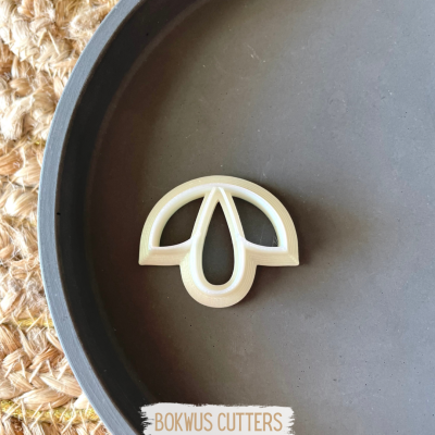 Cortador de biscoitos branco em forma de folha numa placa preta