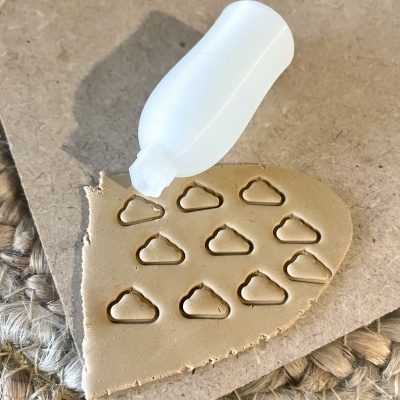 Massa bege com moldes em forma de nuvem cortados e aplicador branco sobre superfície de cartão