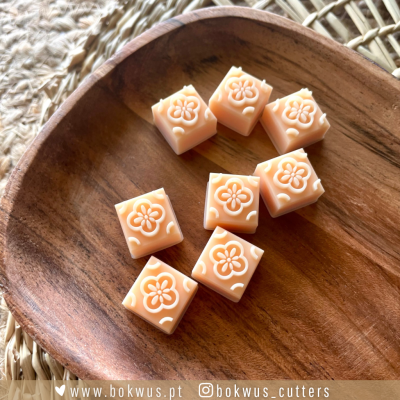 Cubos cor de pêssego com flores gravadas sobre travessa de madeira