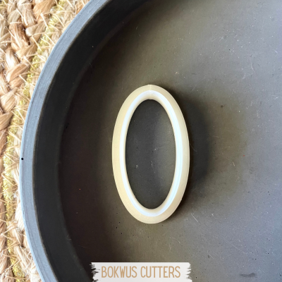 Cortante oval creme e branco numa bandeja preta