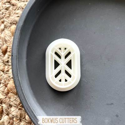 Cortador de bolachas oval branco com padrão geométrico em superfície preta