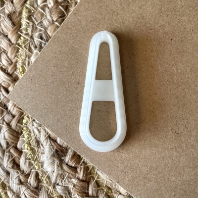 Clips de cabelo em plástico branco sobre cartão castanho e tapete de fibras naturais.