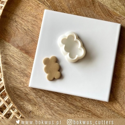 Forma de corte branca em forma de nuvem e bolacha dourada numa placa branca sobre madeira