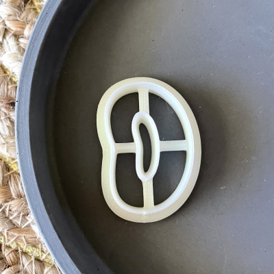 Molde cortador oval branco em base cinzenta e tapete de fibras