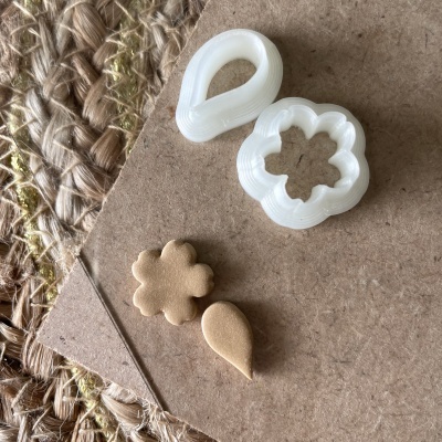 Cortadores de massa de plástico branco e peças de massa cortada sobre cartão castanho e tapete de fibras naturais