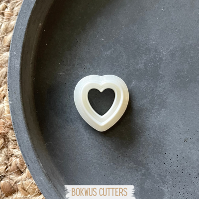 Cortadores de massa em formato de coração brancos dentro de prato preto