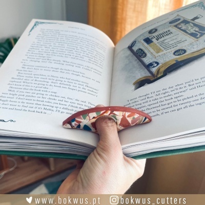 Livro aberto com texto em inglês e apoio de dedo cerâmico colorido