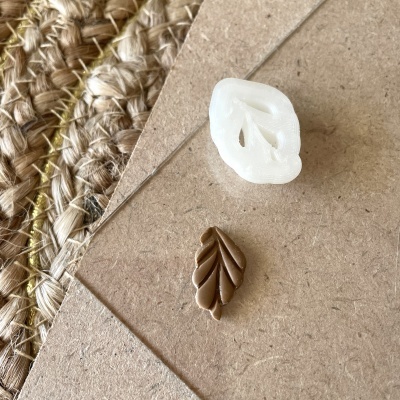 Dois moldes em forma de folha sobre papel castanho reciclado e tapete de fibras naturais