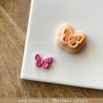 Molde de silicone em forma de borboleta cor pêssego e borboleta rosa sobre superfície branca